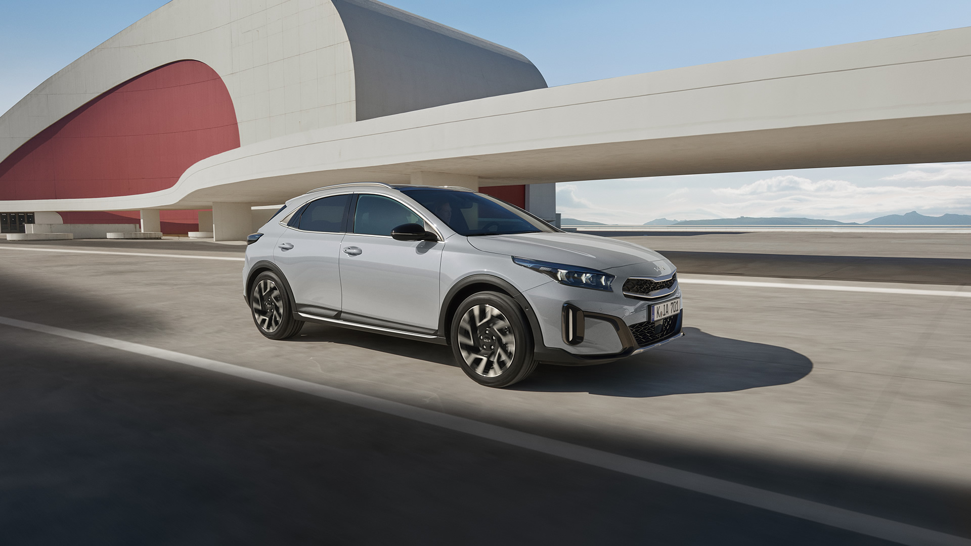 KIA Xceed fährt vo reinem modernen Gebäude.